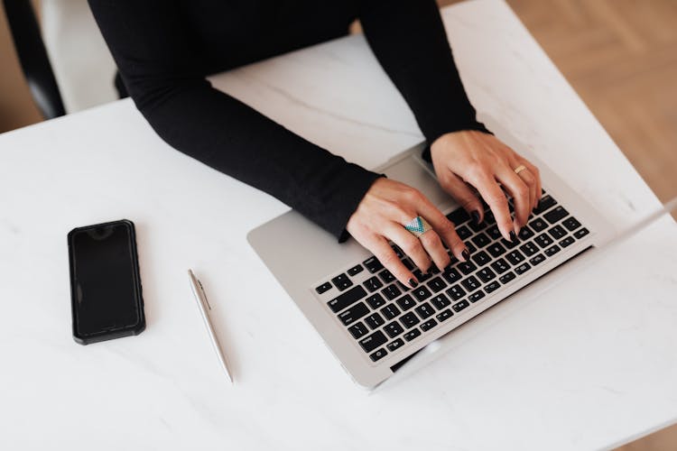 Crop Faceless Woman Using Laptop At Desk In Light Office