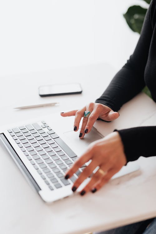 Free Crop female using touchpad on laptop in office Stock Photo