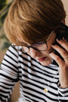 Professional woman in stripes focuses during a phone conversation indoors.