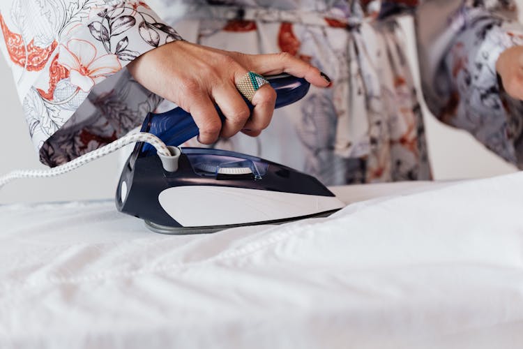 Crop Woman Ironing White Clothes On Ironing Board