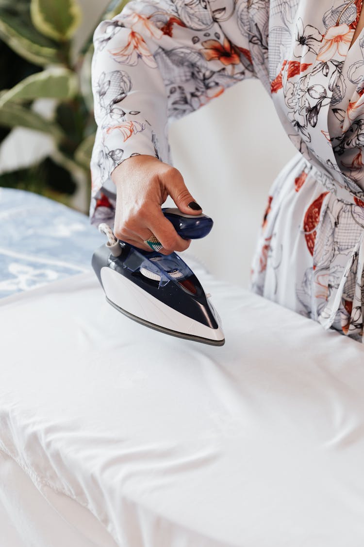 Crop Housewife Ironing White Clothes On Ironing Board