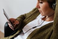 一名女子在室内用智能手机和耳机听音乐