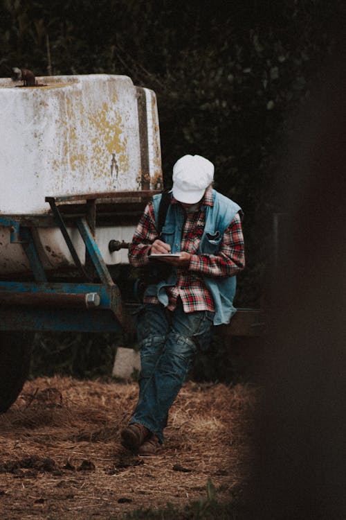 Unrecognizable farmer making notes near trailer