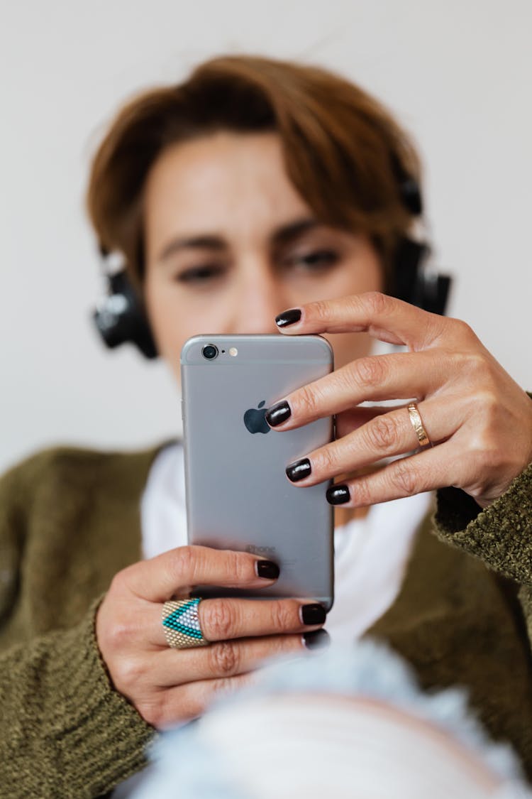 Concentrated Woman In Headphones Browsing Modern Cellphone