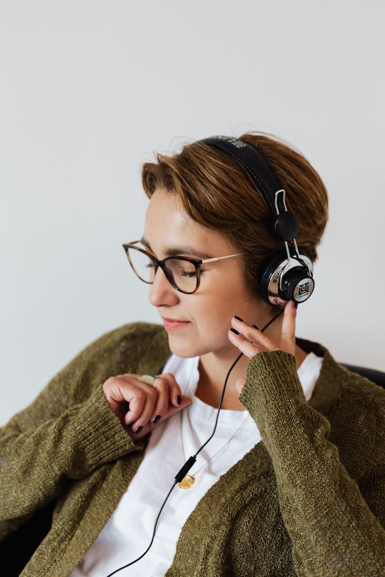 Glad Woman In Eyeglasses Using Headphones