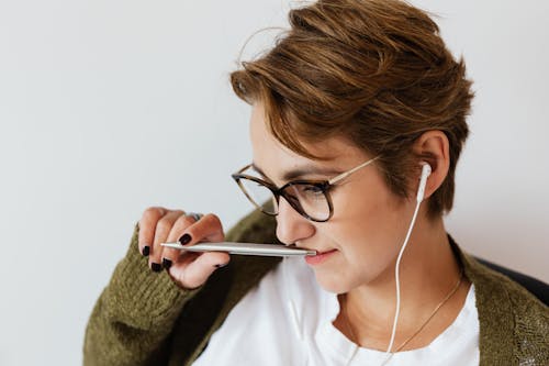 Content woman with earphones and stylish pen
