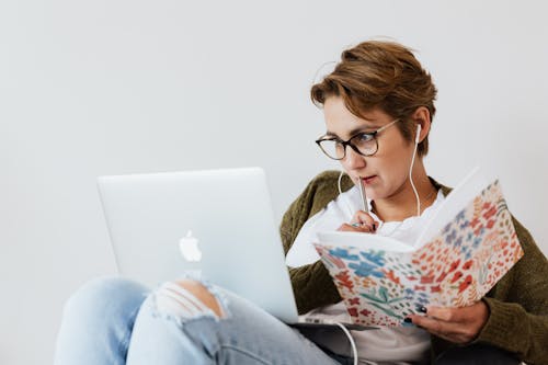 Free Concentrated woman using laptop and taking notes Stock Photo