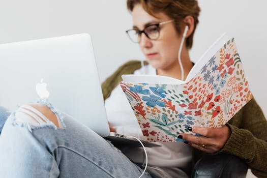 Focused woman studying with a laptop and notebook indoors, wearing earphones.