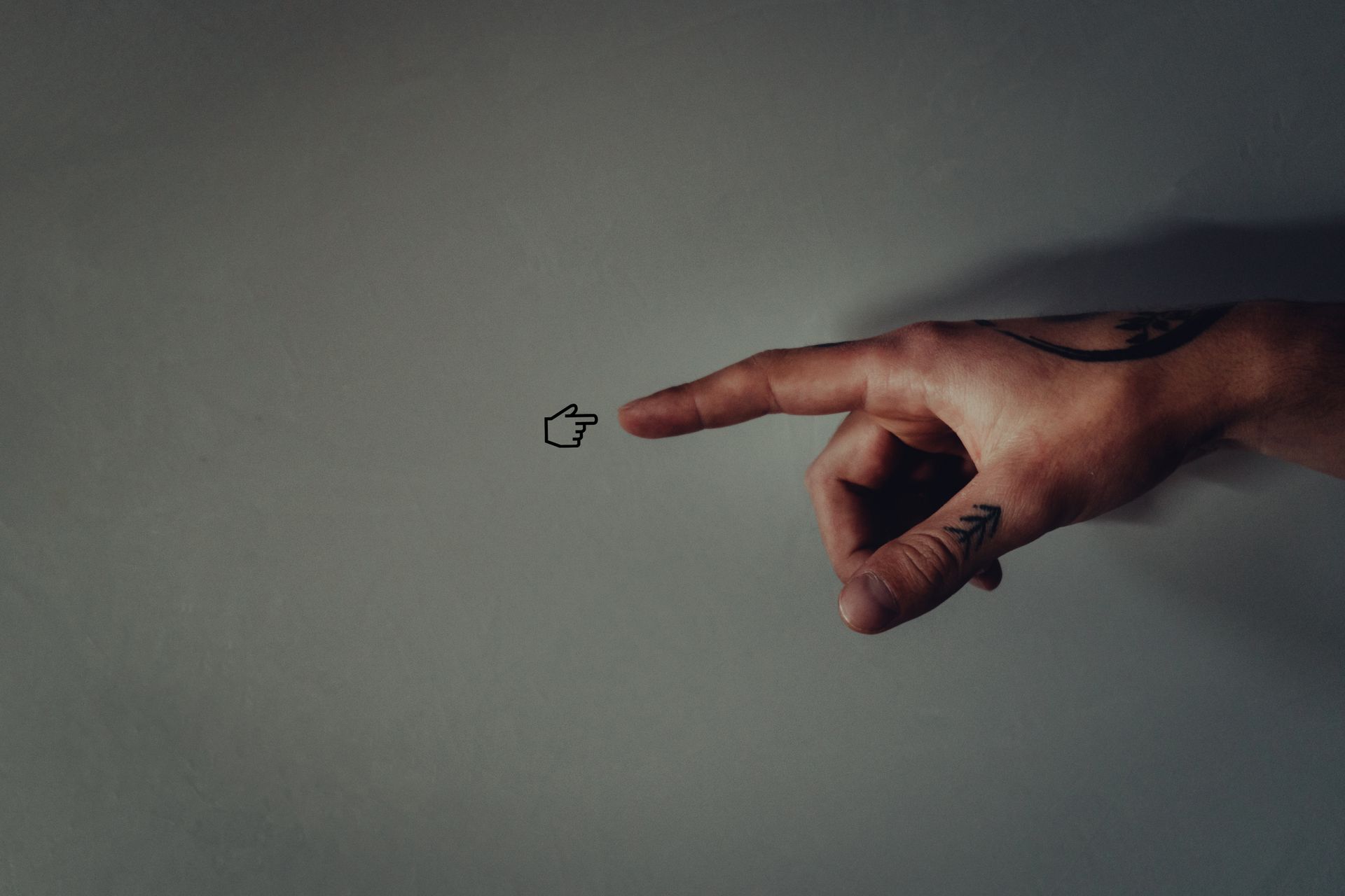 Tattooed hand pointing with a minimalistic arrow tattoo, symbolizing guidance and direction.