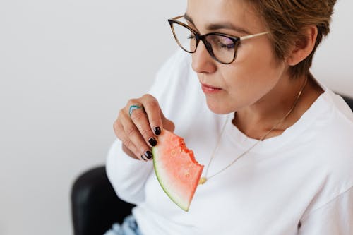 Crop adult lady eating tasty watermelon at home