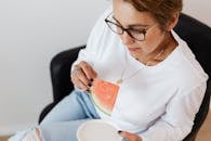 Crop woman eating sweet ripe watermelon sitting in armchair during break