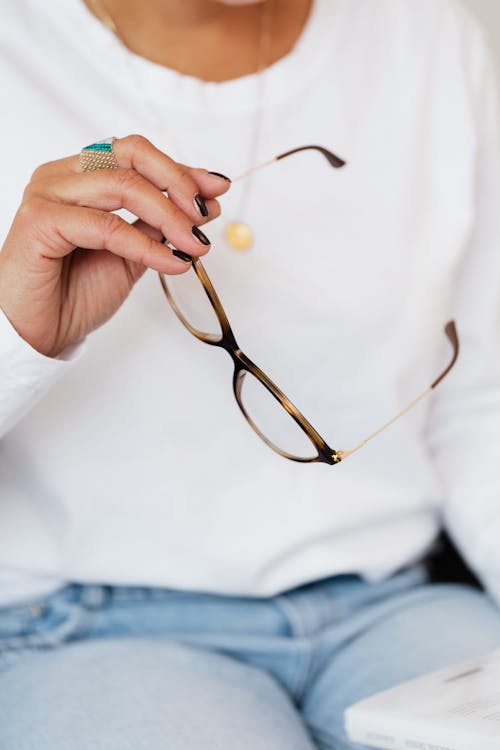 Crop anonymous woman with eyeglasses in hand