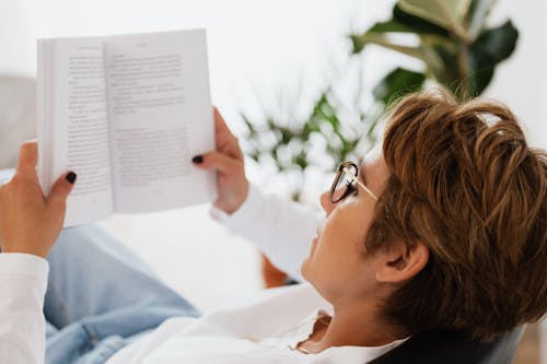 Free Calm woman in eyeglasses relaxing with book Stock Photo