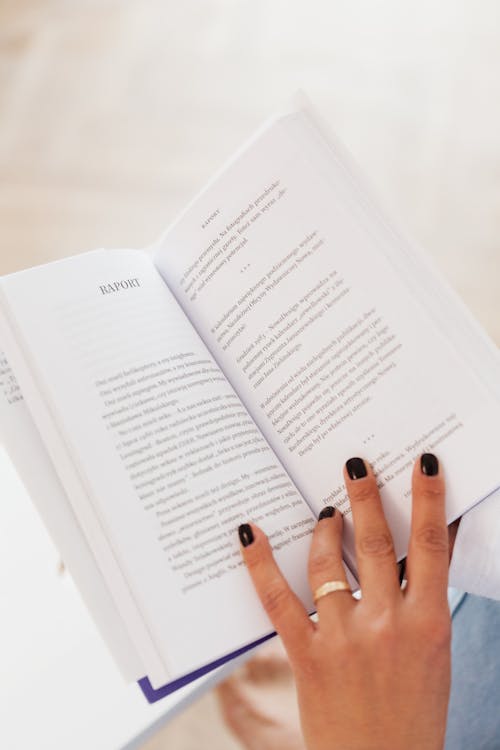 Free From above of anonymous woman with ring on finger resting at home and reading book in daylight Stock Photo