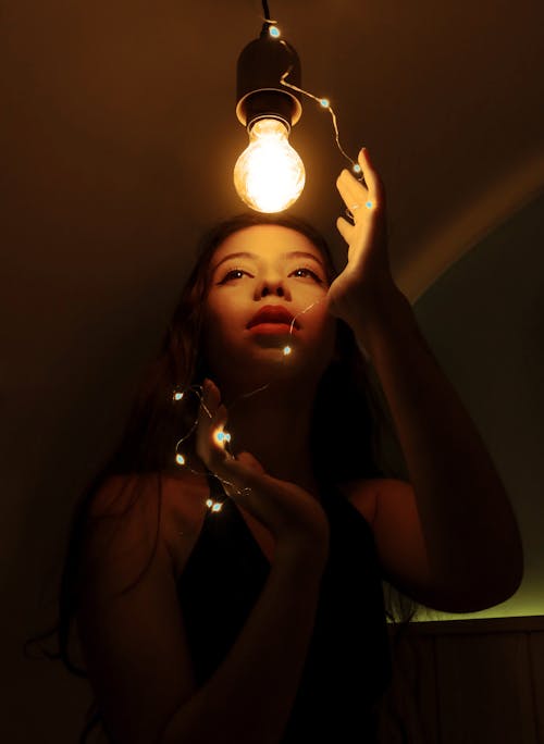Ethnic woman touching light bulb
