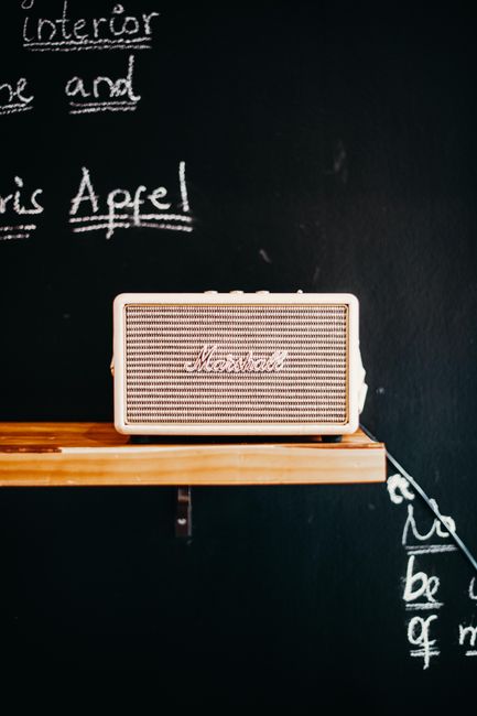 Elegant Marshall Bluetooth speaker on a wooden shelf before a chalkboard backdrop.