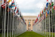 From below of various flags on flagpoles located in green park in front of entrance to the UN headquarters in Geneva