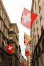 From below bright national flag of Switzerland on stone houses of narrow street of Geneva