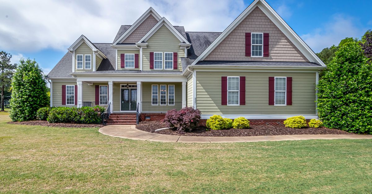 Beautiful two-story suburban house with manicured lawn and front porch.