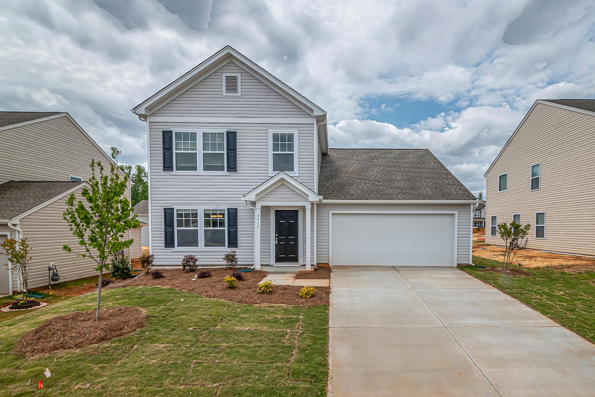 Newly built two-story house with a landscaped yard in a suburban neighborhood.