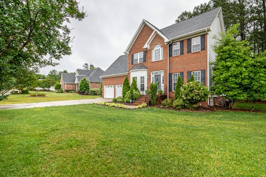 Charming two-story brick house with manicured lawn and trees, perfect family home.