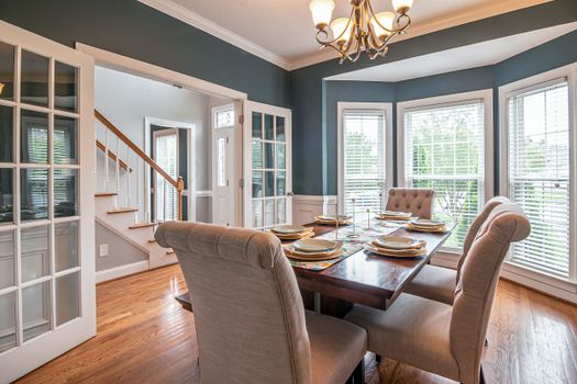 A beautifully set dining room table in a well-lit home interior, showcasing elegant decor and furniture.