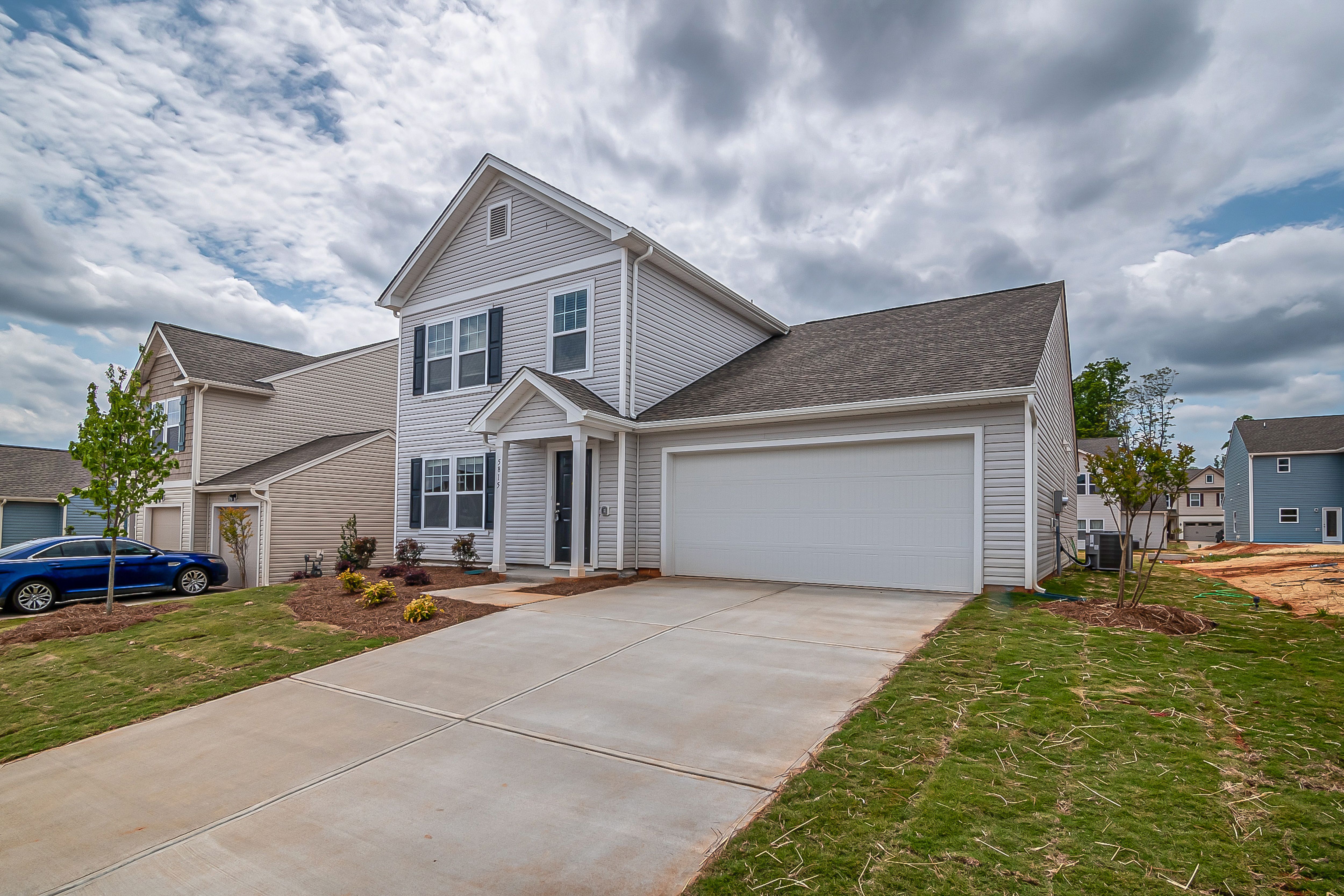 Alt Text: A two-story brick suburban house with a well-manicured green lawn, clean concrete driveway, and strong exterior curb appeal.