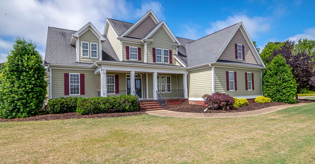 Beautiful suburban house with a well-maintained lawn under a clear blue sky.