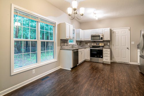 White Wooden Kitchen Cabinet Near White Wooden Framed Glass Window