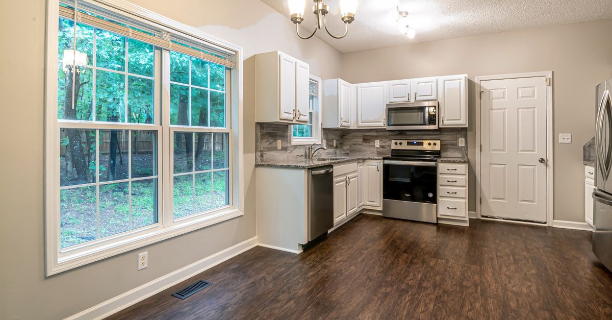 Spacious kitchen featuring modern appliances, large windows, and stylish cabinetry.
