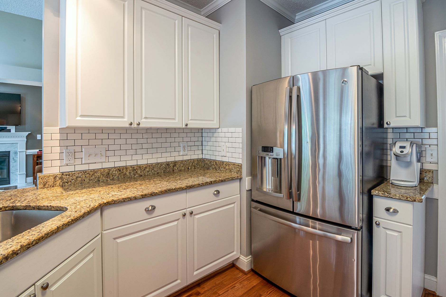 Bright modern kitchen with granite countertops, stainless steel appliances, and white cabinetry.