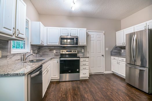Bright modern kitchen featuring white cabinets and stainless steel appliances.