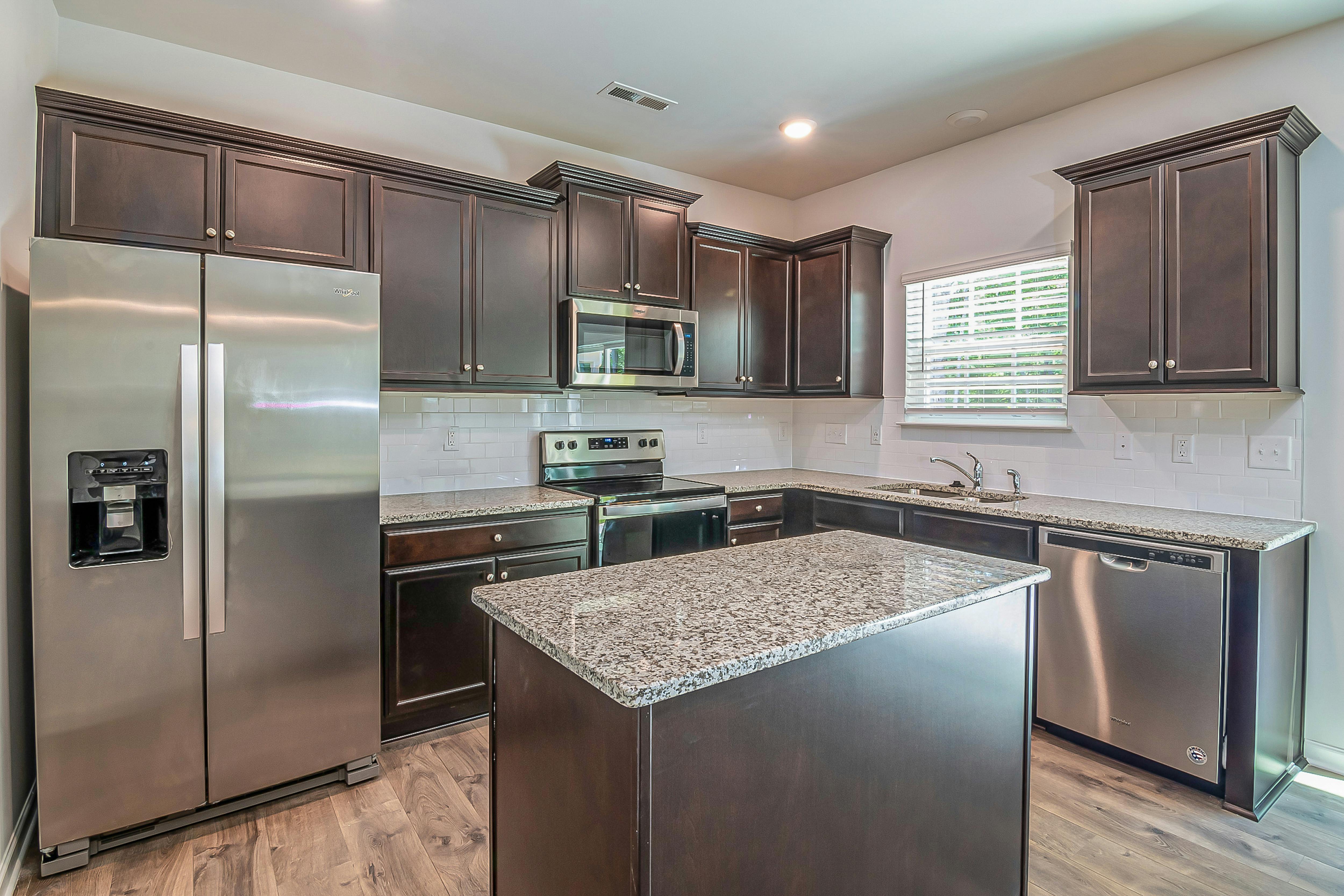 Spacious kitchen with stainless steel appliances and sleek dark wood cabinetry.