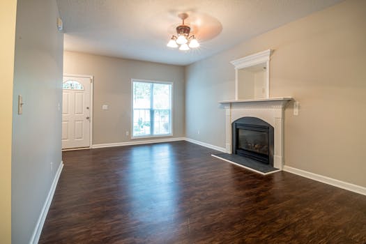 Spacious empty living room with fireplace, hardwood floors, and bright natural light.