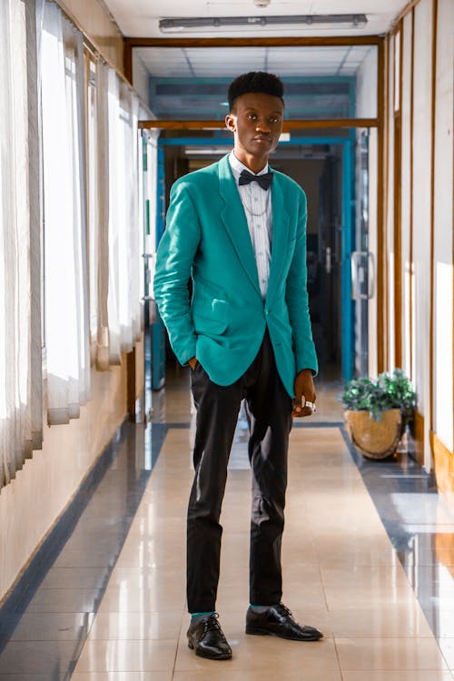 Man Wearing a Turquoise Jacket, Standing in a Corridor