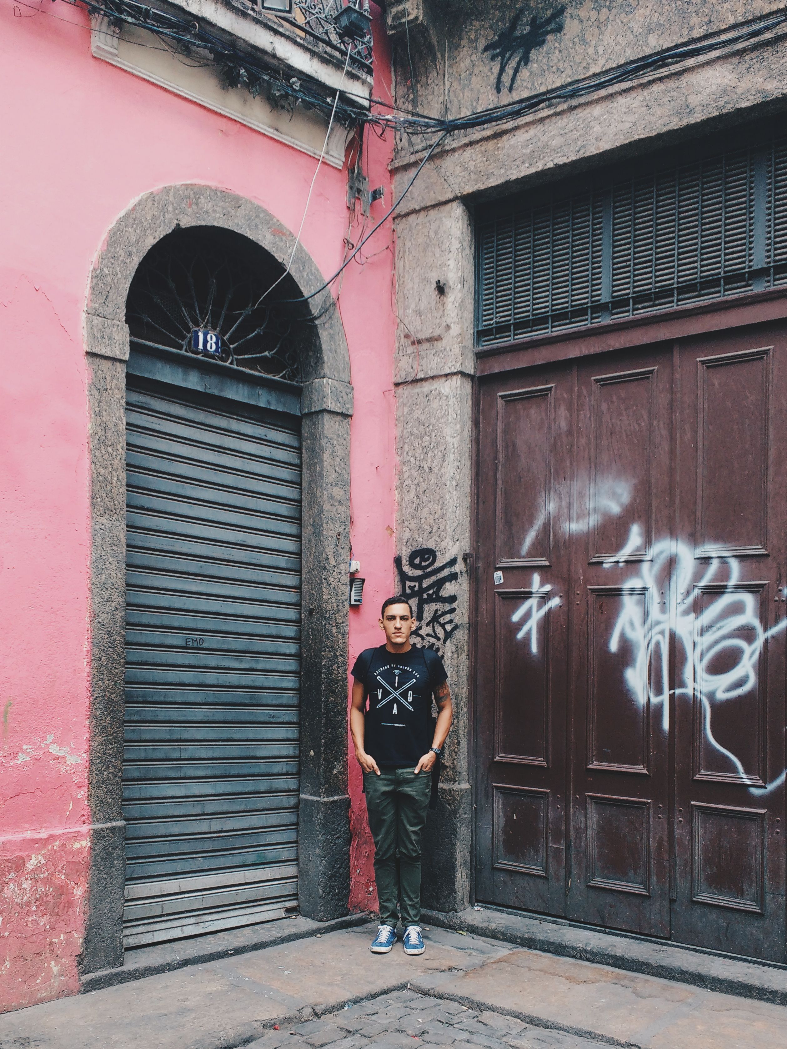 Man standing in front of a graffiti-covered wall in Rio de Janeiro, showcasing urban culture.