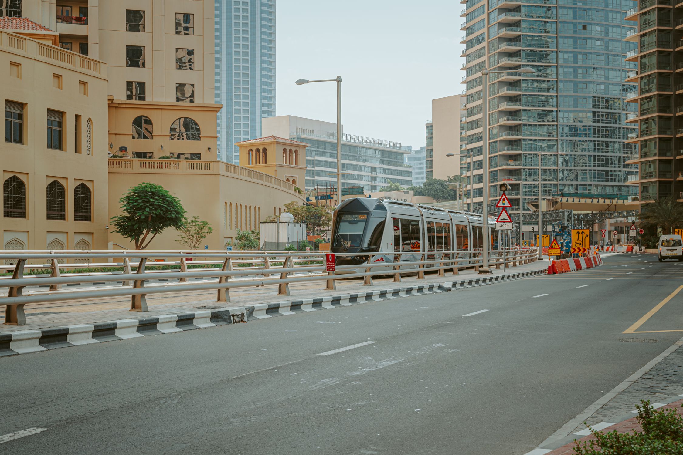Modern metro train moving along high towers and road in central district of city