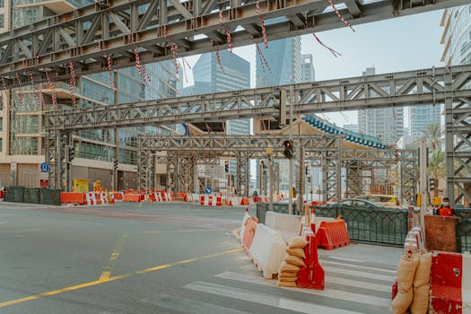 A busy urban street in Dubai featuring elevated construction with skyscrapers in the background.