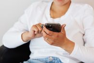 穿着休闲装的妇女坐在室内，使用智能手机享受闲暇时光