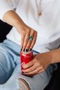 From above of crop faceless stylish female with manicure and rings opening bright can of cold coke while resting at home