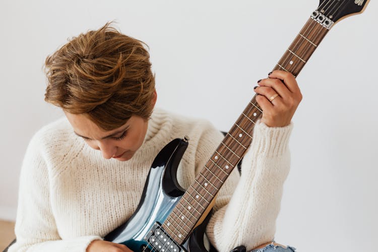 Pensive Woman In White Sweater With Electric Guitar