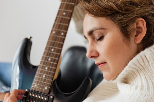 Calm woman playing electric guitar with closed eyes
