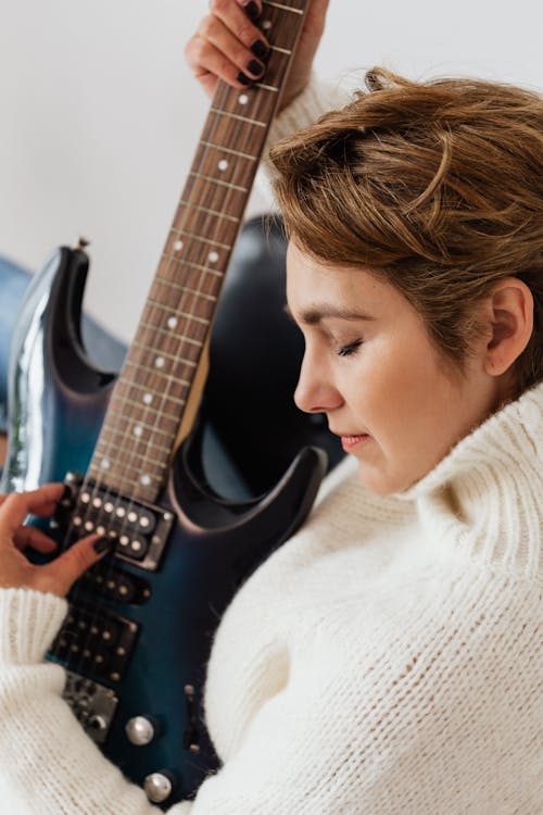 Calm adult lady playing guitar in armchair