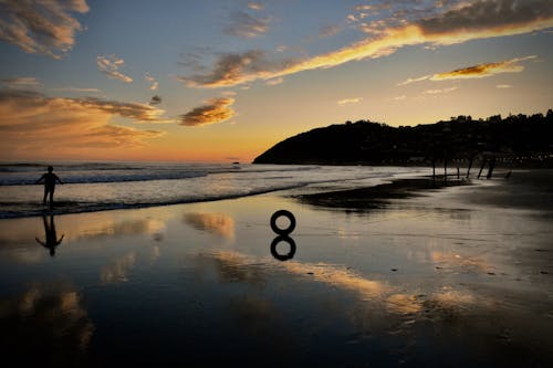 Silhouette of a Person Standing on the Beach during Golden Hour