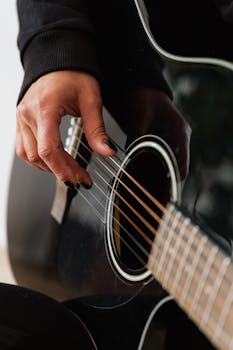 A detailed shot of a hand playing an acoustic guitar, focusing on the strings.