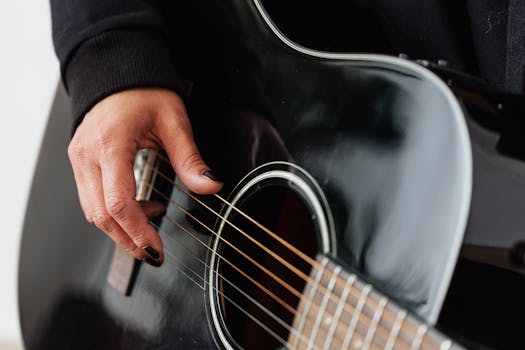 Detailed view of a person strumming an acoustic guitar, focusing on the guitar strings and hand.