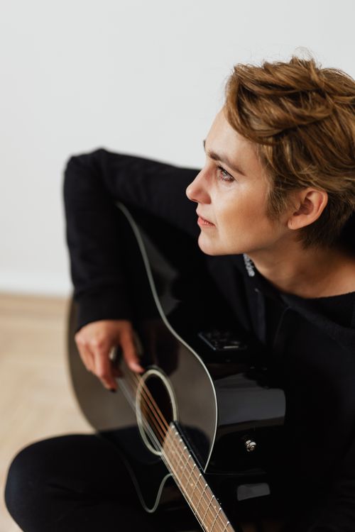 Free A pensive musician playing an acoustic guitar, focused and serious in expression. Stock Photo