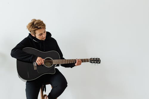 Person in Black Hoodie Playing Acoustic Guitar
