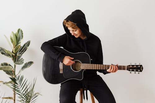 Free Cheerful female guitarist improving chord playing technique Stock Photo