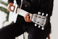 Crop unrecognizable female musician playing classic guitar in flat